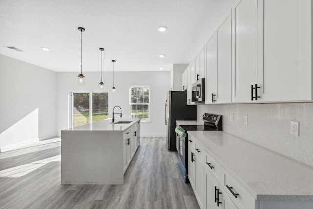 kitchen featuring tasteful backsplash, a center island with sink, appliances with stainless steel finishes, light wood-type flooring, and a sink