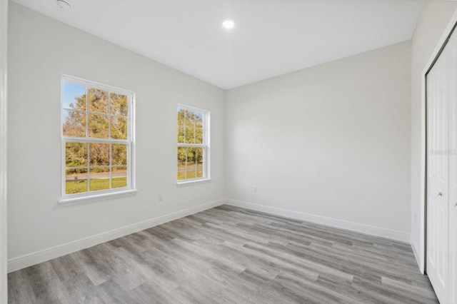 unfurnished bedroom featuring light wood-style floors, baseboards, and a closet