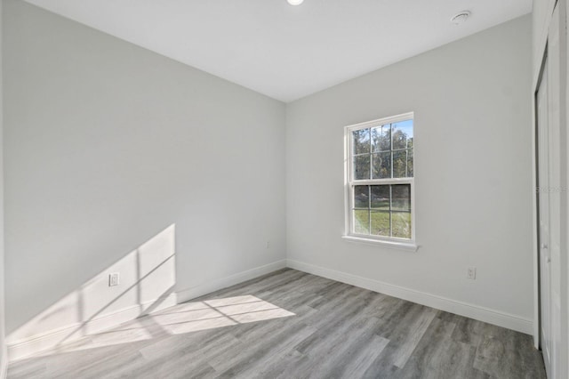 spare room with baseboards and wood finished floors