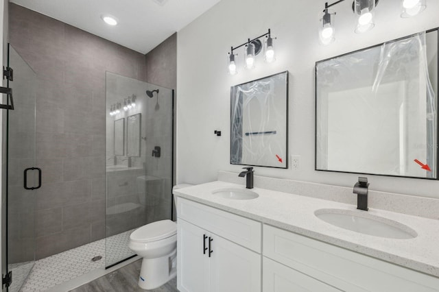 bathroom with a sink, a shower stall, toilet, and double vanity