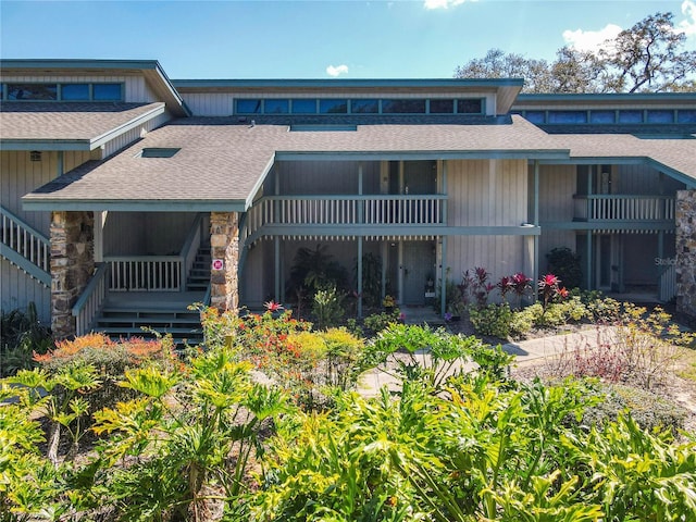 rear view of house featuring stairway and roof with shingles