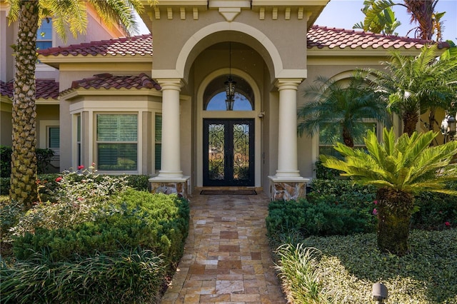 entrance to property featuring stucco siding, a tiled roof, and french doors