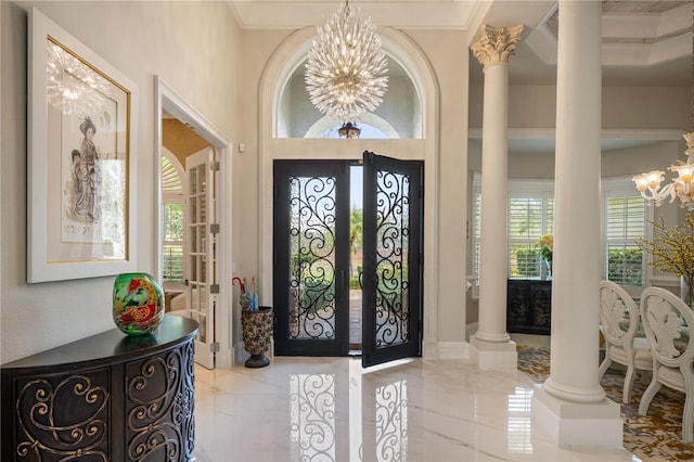 entryway with a notable chandelier, marble finish floor, french doors, and ornate columns