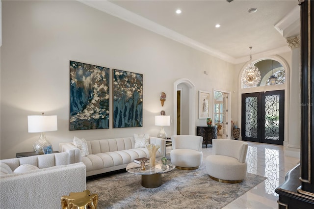 living area featuring crown molding, recessed lighting, french doors, a towering ceiling, and a notable chandelier