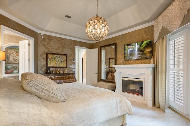 bedroom with visible vents, a tray ceiling, an inviting chandelier, a glass covered fireplace, and crown molding