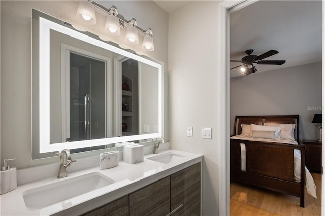 full bath with a ceiling fan, double vanity, wood finished floors, and a sink