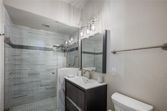 bathroom featuring toilet, a stall shower, vanity, and a textured wall