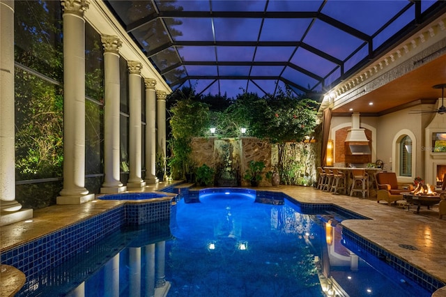 view of swimming pool with glass enclosure, a patio, a ceiling fan, a pool with connected hot tub, and outdoor dry bar