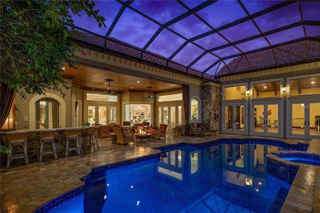 view of swimming pool with glass enclosure, a pool with connected hot tub, french doors, a patio area, and outdoor dry bar