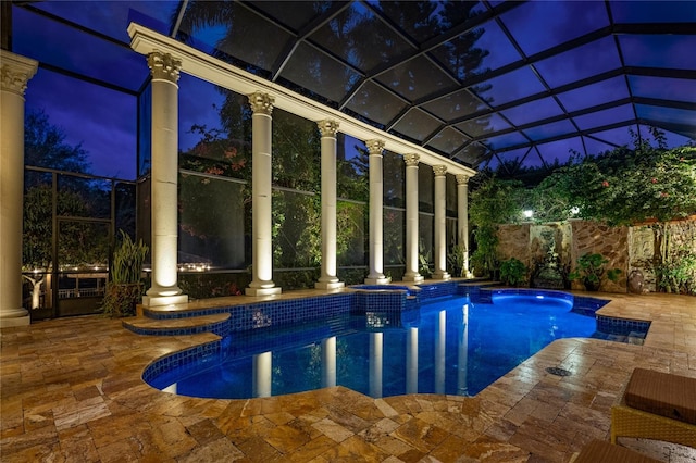 pool at twilight with a patio, a lanai, and a pool with connected hot tub