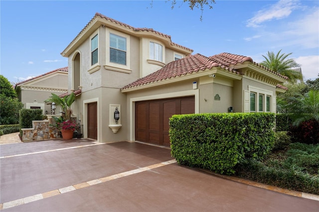 mediterranean / spanish house featuring stucco siding, concrete driveway, and a tile roof