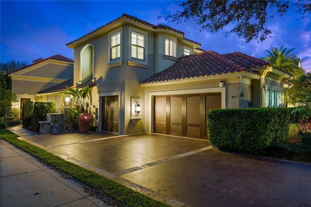 mediterranean / spanish-style house featuring a tiled roof, driveway, and stucco siding