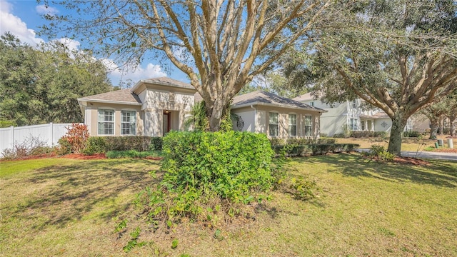 ranch-style house featuring fence, a front lawn, and stucco siding