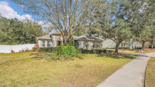 view of front facade featuring fence, a front lawn, and stucco siding