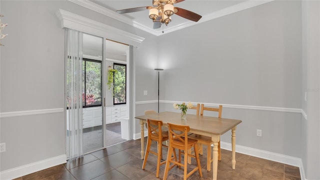 dining room featuring ornamental molding, dark tile patterned floors, a ceiling fan, and baseboards