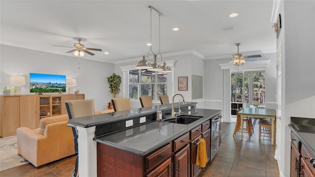 kitchen with dark countertops, a kitchen island, a sink, dishwasher, and a kitchen bar