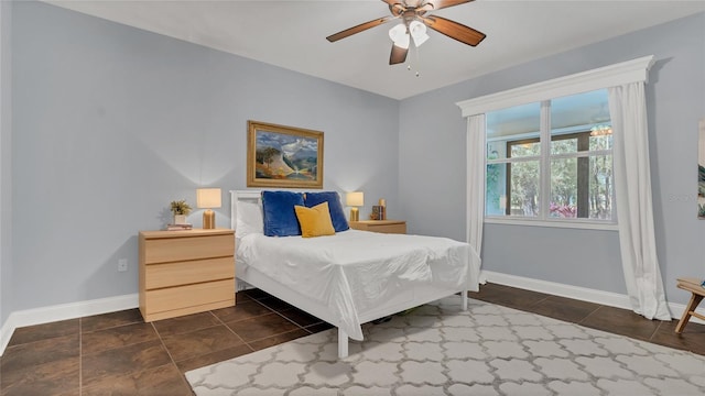 bedroom featuring a ceiling fan, dark tile patterned flooring, and baseboards