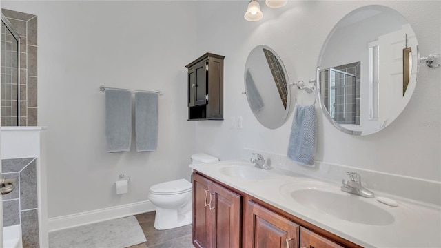 full bath featuring tiled shower, a sink, toilet, and double vanity