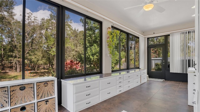 unfurnished sunroom featuring ceiling fan and a wealth of natural light