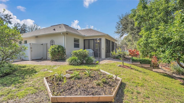 back of house with a garden, a yard, a sunroom, and stucco siding