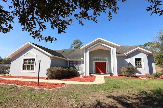 ranch-style home featuring a front lawn and stucco siding