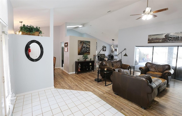 living room with a ceiling fan, high vaulted ceiling, light wood-style flooring, and baseboards