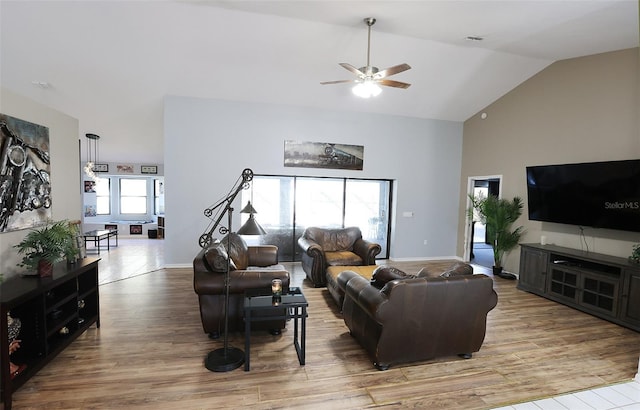 living room featuring high vaulted ceiling, baseboards, ceiling fan, and light wood finished floors