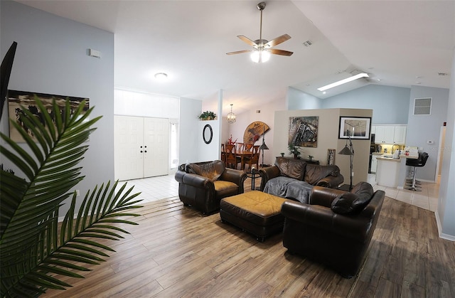 living room featuring light wood-style floors, lofted ceiling, and visible vents