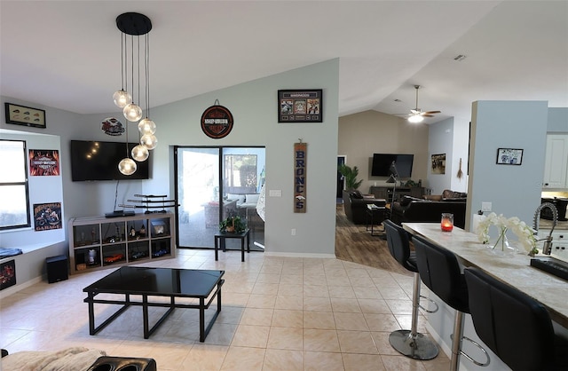 living room featuring lofted ceiling, ceiling fan, baseboards, and light tile patterned floors