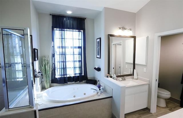 full bath featuring toilet, a tub with jets, wood finished floors, and vanity