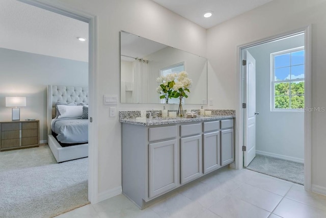 ensuite bathroom with double vanity, baseboards, ensuite bathroom, tile patterned flooring, and recessed lighting