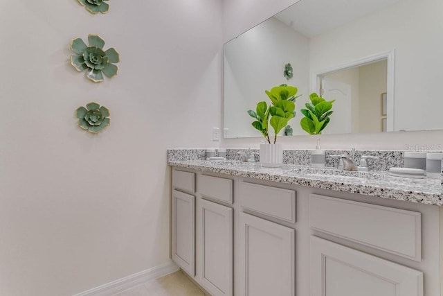 bathroom featuring double vanity, a sink, and baseboards