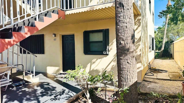 doorway to property featuring fence and stucco siding