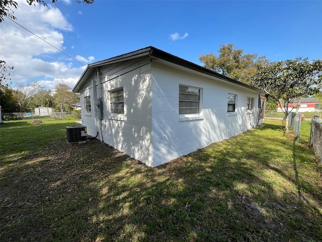 view of property exterior featuring central AC, fence, and a lawn