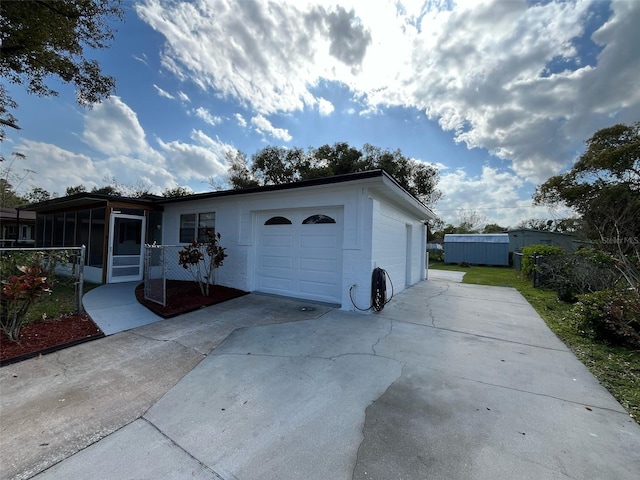 exterior space featuring an attached garage, a sunroom, driveway, and concrete block siding