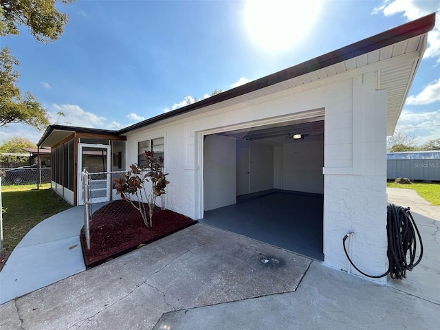 exterior space featuring an attached garage, a sunroom, fence, and concrete driveway