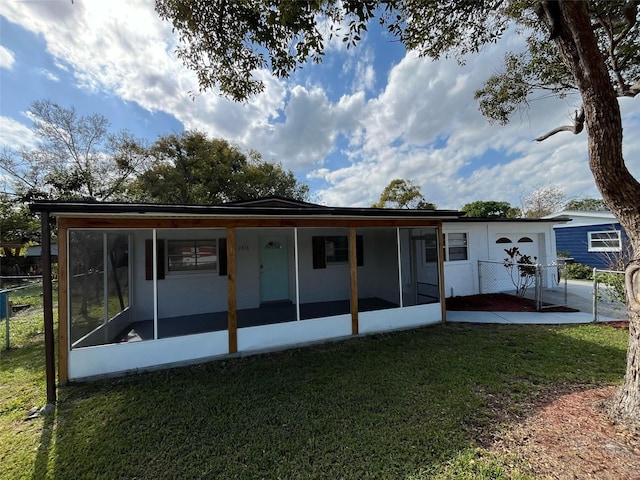 back of property with a sunroom and a yard