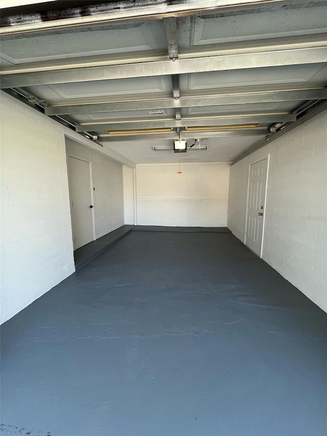 garage featuring concrete block wall and a garage door opener