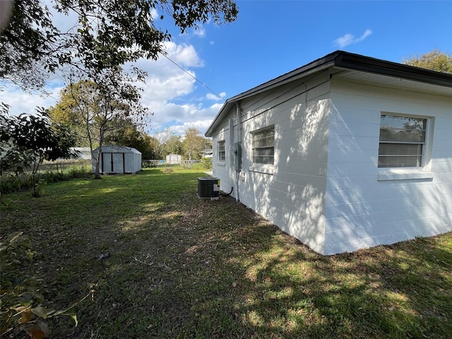 view of property exterior with an outbuilding, a yard, central AC unit, fence, and a shed