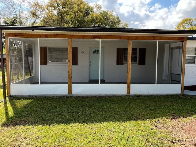 back of house with a sunroom and a lawn