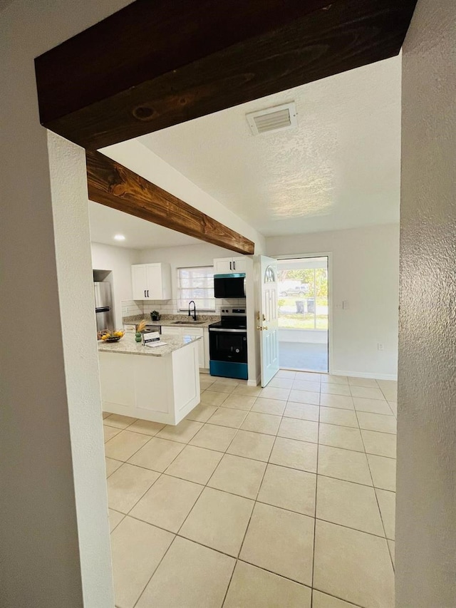 kitchen featuring light tile patterned floors, visible vents, appliances with stainless steel finishes, white cabinets, and a sink