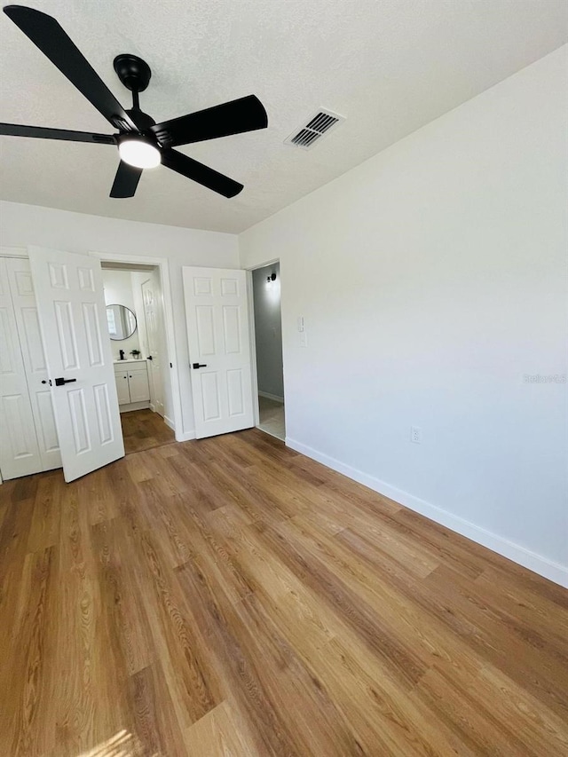 unfurnished bedroom featuring baseboards, visible vents, a ceiling fan, a textured ceiling, and light wood-style floors