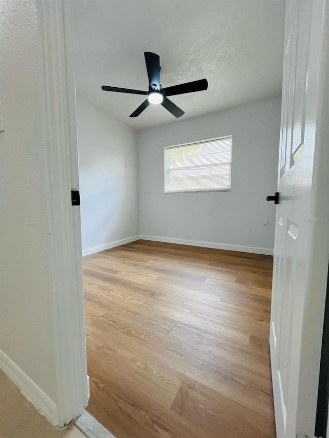 empty room featuring light wood-type flooring, ceiling fan, and baseboards