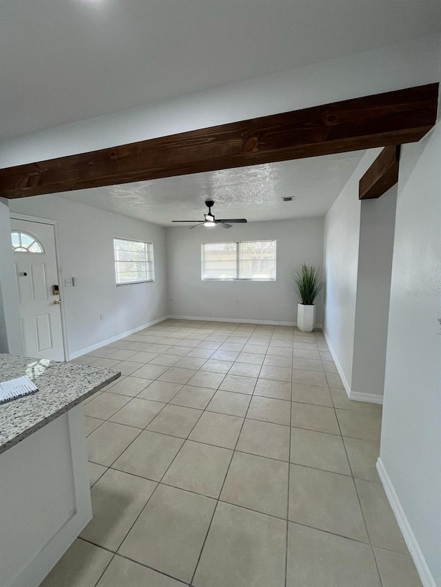 spare room featuring light tile patterned flooring, ceiling fan, a textured ceiling, beamed ceiling, and baseboards