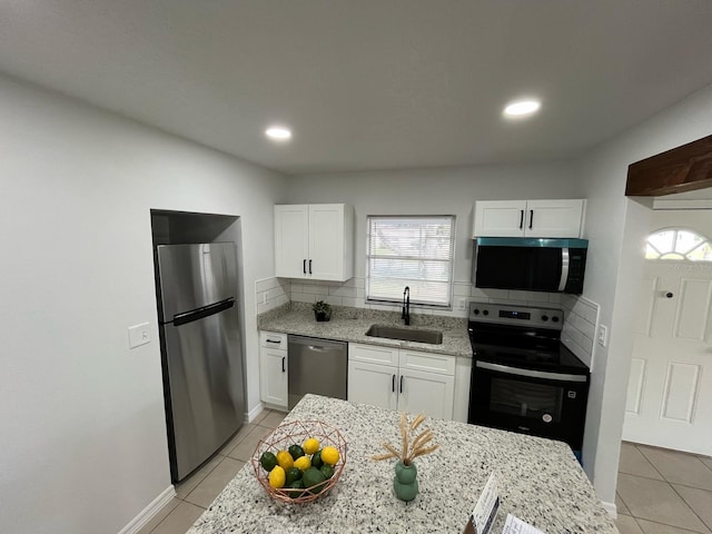 kitchen with appliances with stainless steel finishes, white cabinetry, a sink, and light tile patterned flooring