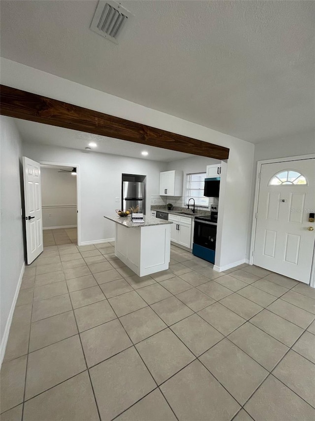 kitchen with light tile patterned floors, a sink, visible vents, electric stove, and freestanding refrigerator