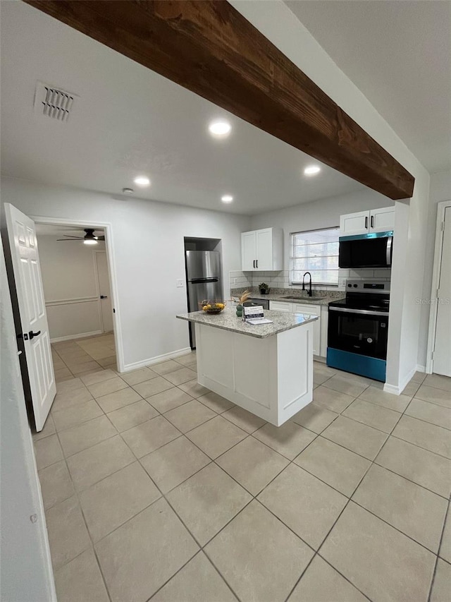 kitchen with light tile patterned flooring, stainless steel appliances, visible vents, white cabinetry, and decorative backsplash