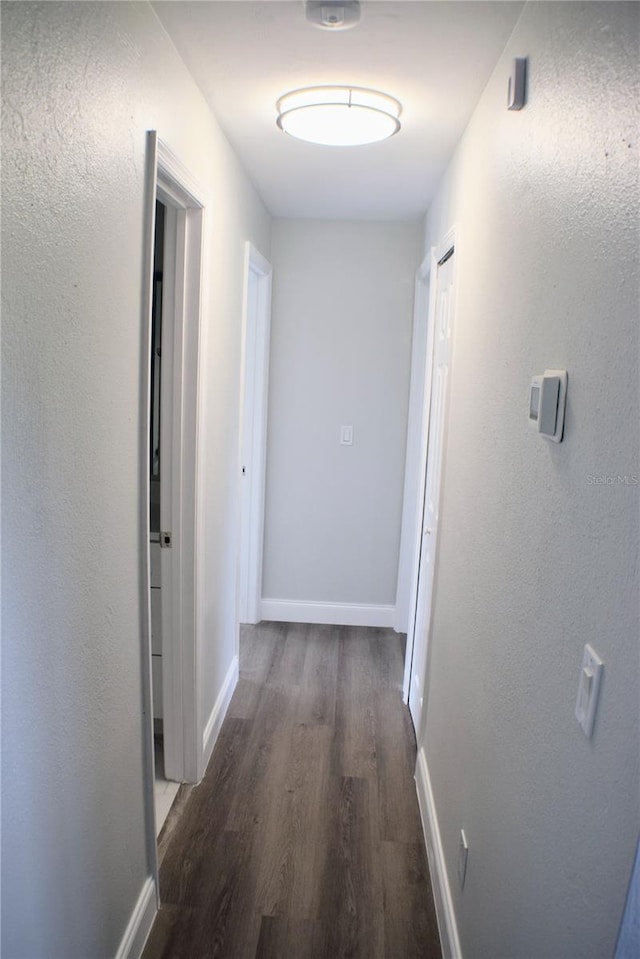 hallway with dark wood-style flooring and baseboards