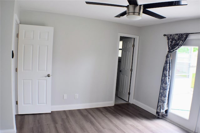 empty room with wood finished floors, a ceiling fan, and baseboards