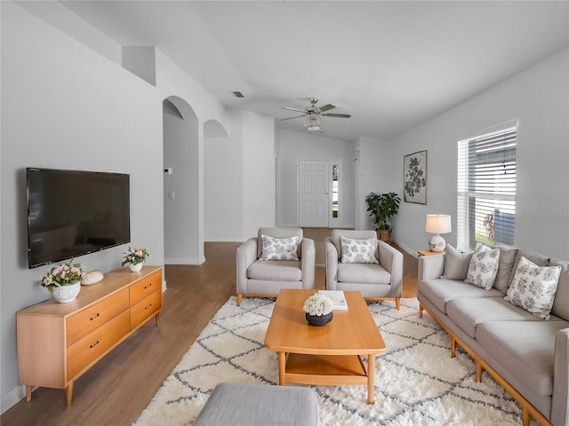 living room with visible vents, arched walkways, ceiling fan, wood finished floors, and vaulted ceiling